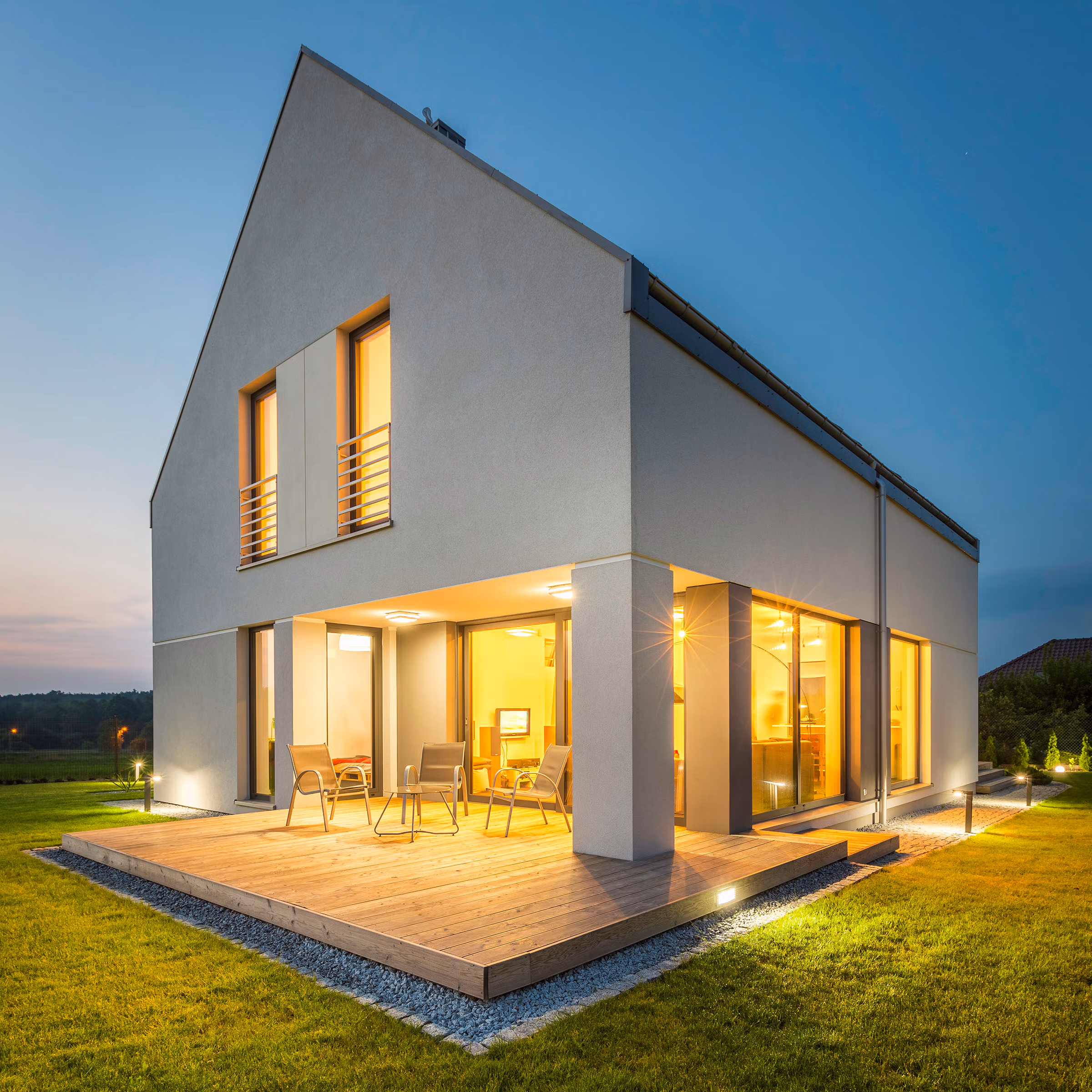 Modern house with illuminated decking and garden at dusk