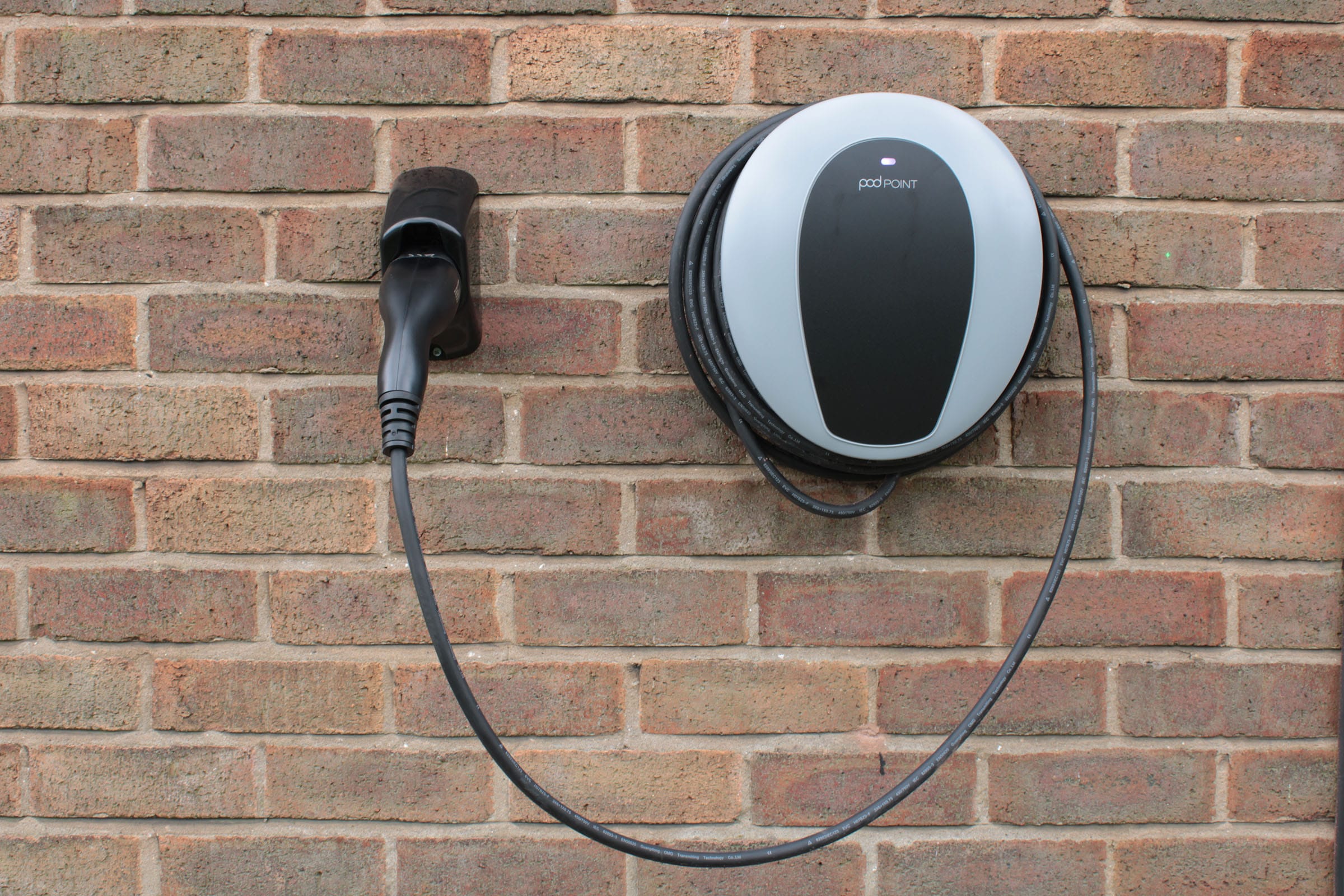 Pod Point home electric vehicle charger mounted on brick wall